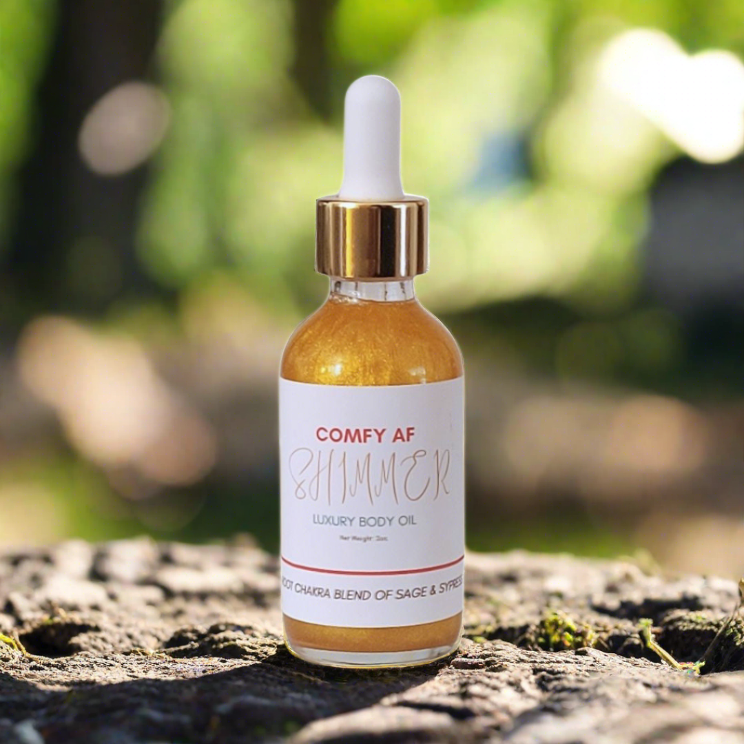 
                  
                    Comfy AF Shimmer Body Oil sitting on soil with blurred trees in the background
                  
                